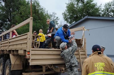 Residents and children being helped onto a National Guard truck by soldiers and a Lyons firefighter during the 2013 flood evacuation