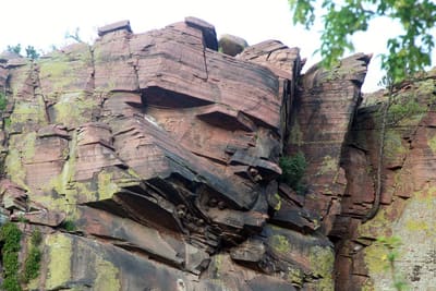 Layered red sandstone cliff face above trees at Planet Bluegrass