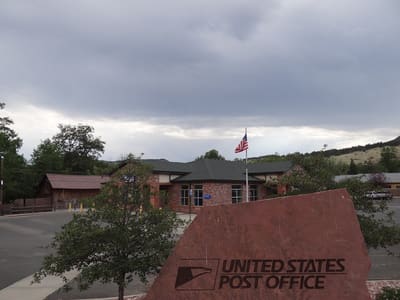 The red-roofed Lyons post office under a grey sky, flag flying