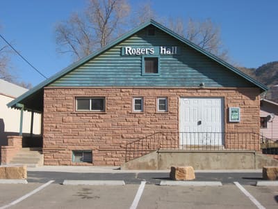 Rogers Hall, a gabled red sandstone building with a green-shingled upper storey and a white double door