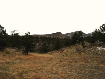 A meadow at dusk with the red sandstone hogback beyond, just west of Lyons on US 36